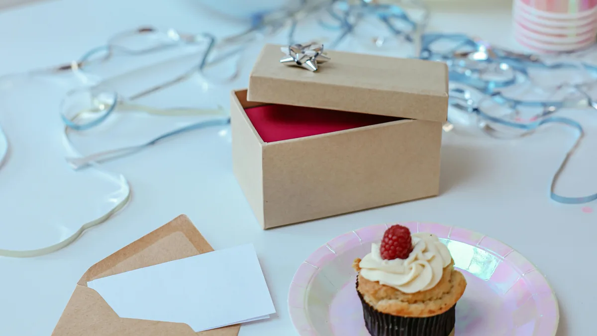 Birthday surprise box idea with an open gift box, blank clue card, envelope, cupcake, and party decorations.