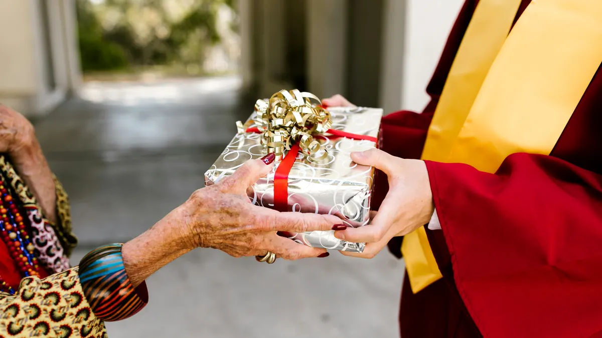 Close-up of a graduate receiving a wrapped graduation gift as a reveal moment.